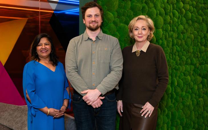 Three people in front of moss wall