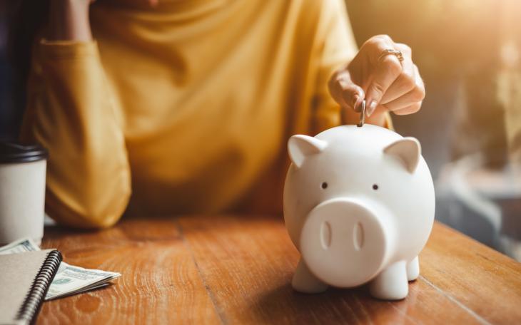 young woman putting pennies into piggy bank
