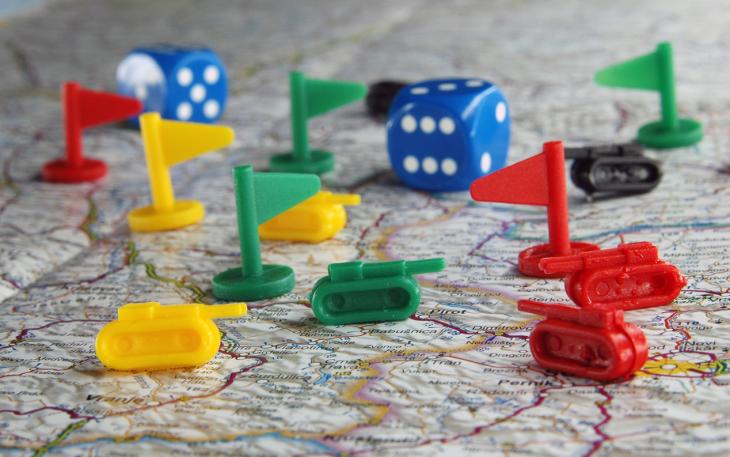 toy flags and tanks and dice sit on a map of the world