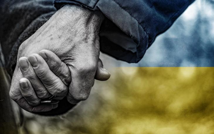 hands held in front of Ukrainian flag