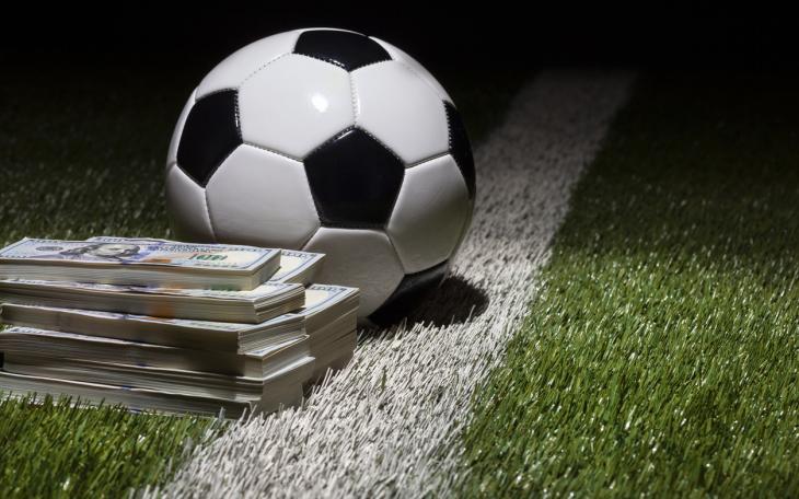 football on pitch next to wad of cash