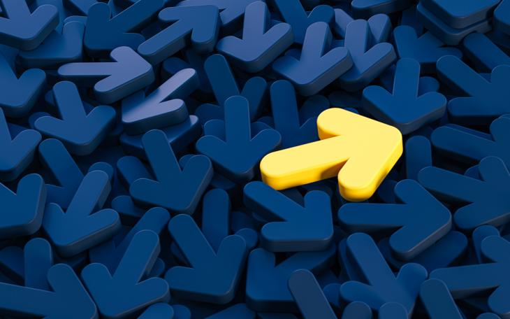 yellow plastic arrow in sea of navy arrows