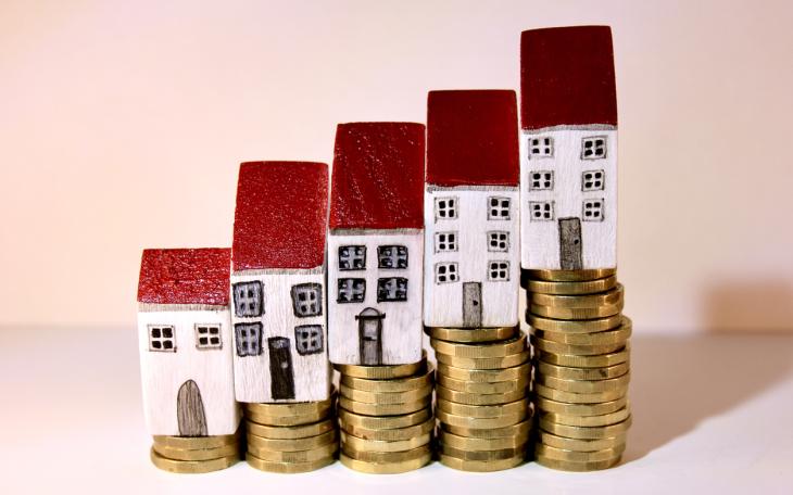 toy houses stacked on coins