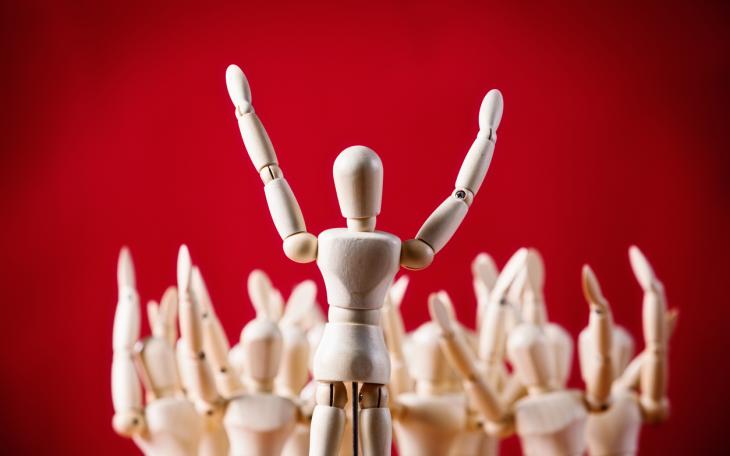 wooden figure speaking to crowd red background