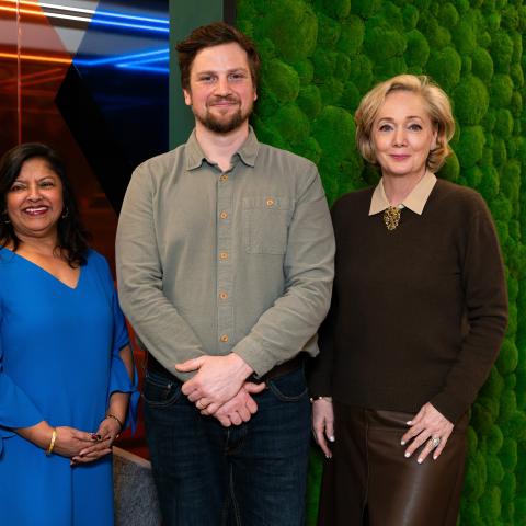 Three people in front of moss wall