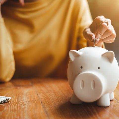young woman putting pennies into piggy bank
