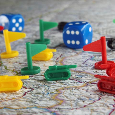 toy flags and tanks and dice sit on a map of the world