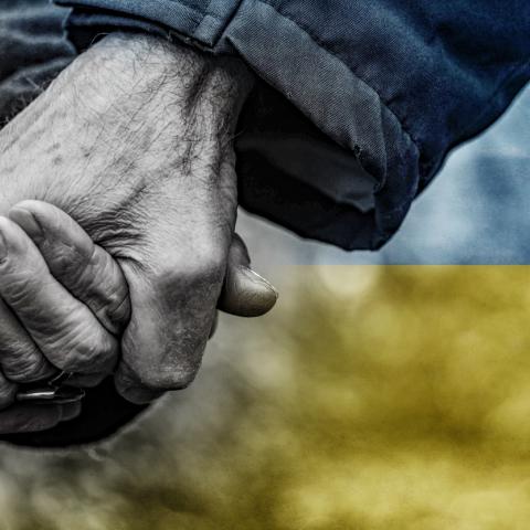hands held in front of Ukrainian flag