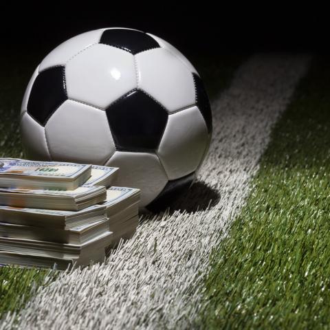 football on pitch next to wad of cash