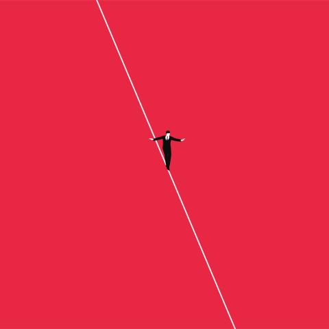 business man in suit walking a tightrope with red background 
