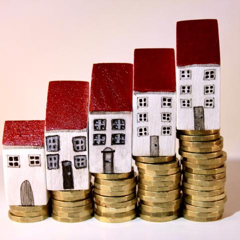 toy houses stacked on coins