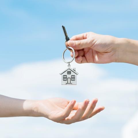someone handing over a key with the blue sky in the background
