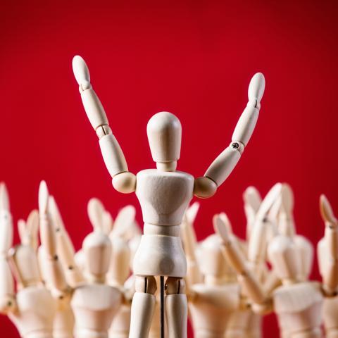 wooden figure speaking to crowd red background